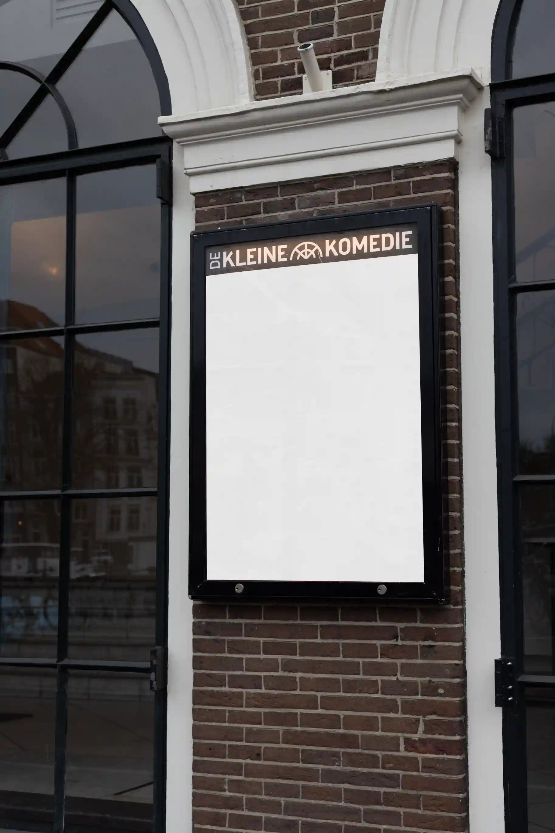 City light poster mockup in front of De Kleine Komedie theater in Amsterdam with bold red poster design.