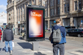 Amsterdam city light poster mockup at Dam Square with pedestrians and urban architecture.