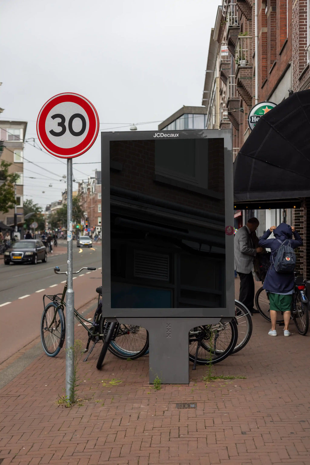 Blank screen Amsterdam De Pijp city light advertising mockup in frontal perspective located on a busy urban street in Amsterdam, Netherlands.