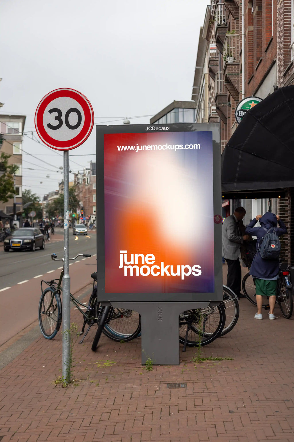 Front view Amsterdam De Pijp city light advertising mockup on a sidewalk with street traffic, bicycles and classic Amsterdam architecture in the background.