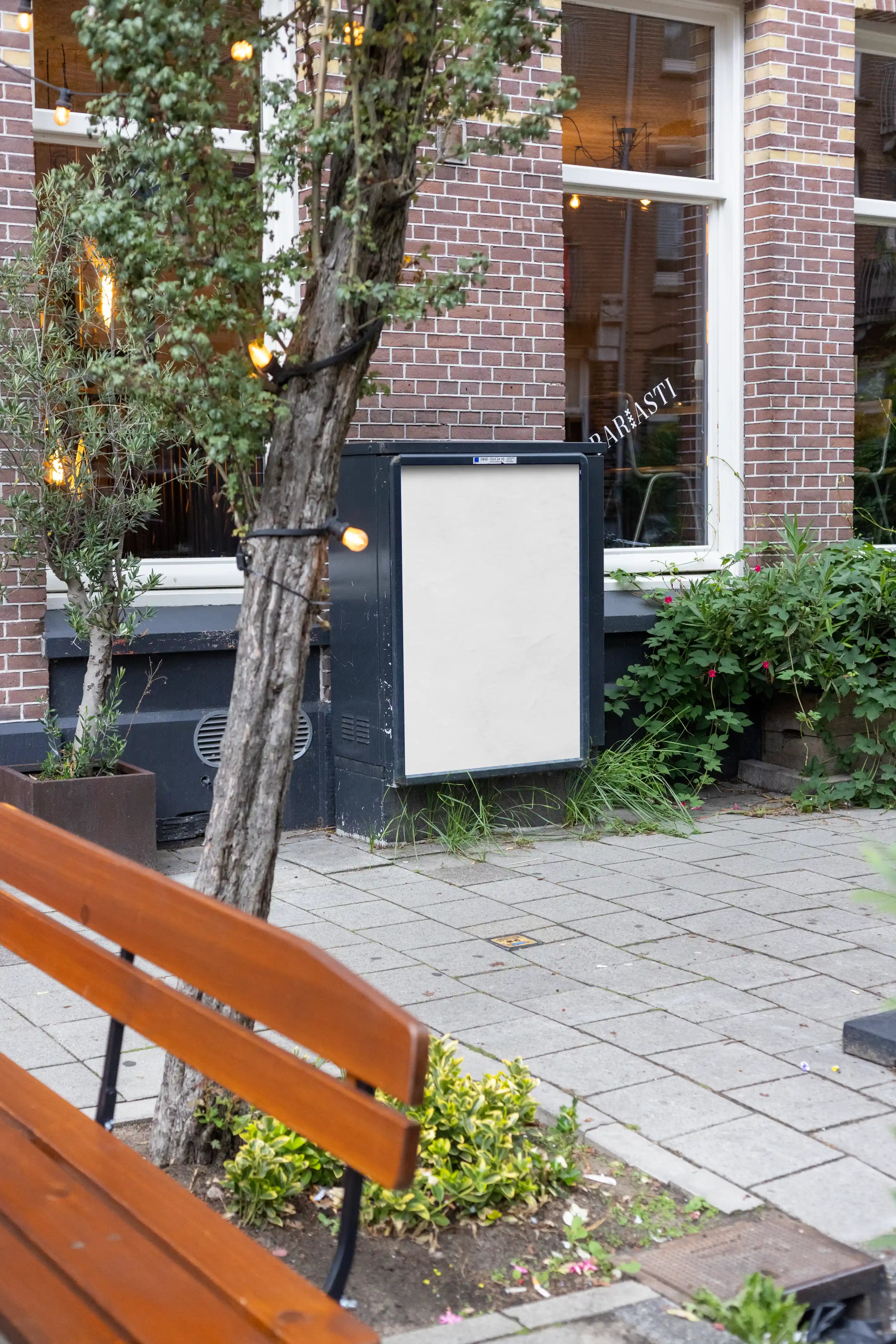 Blank background Amsterdam De Pijp poster display mockup in DIN format positioned on a sidewalk in front of a traditional brick building in Amsterdam, Netherlands.