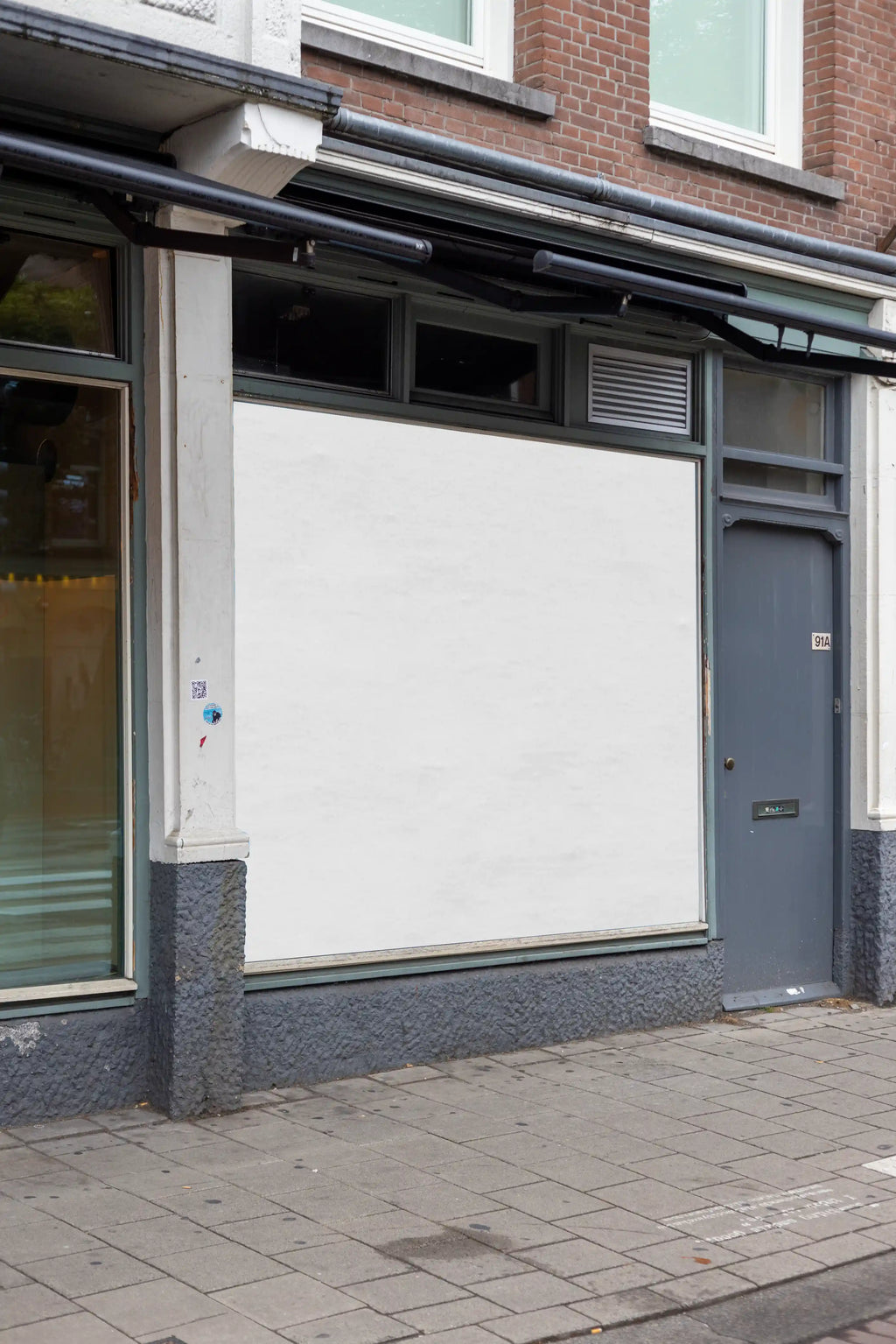 Blank background window square poster mockup in Amsterdam De Pijp with realistic storefront facade, high resolution PSD template ideal for custom branding and advertising design.