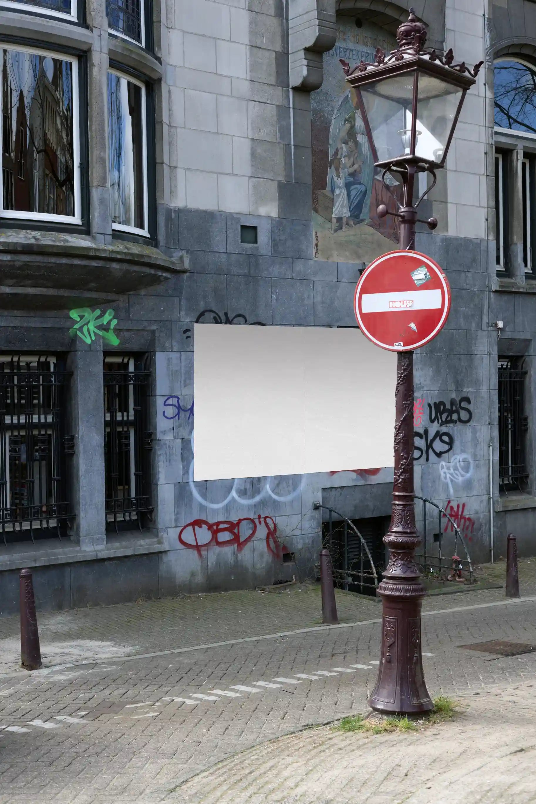 Two large urban posters on a graffiti-covered wall in Amsterdam with a vintage street lamp in front.
