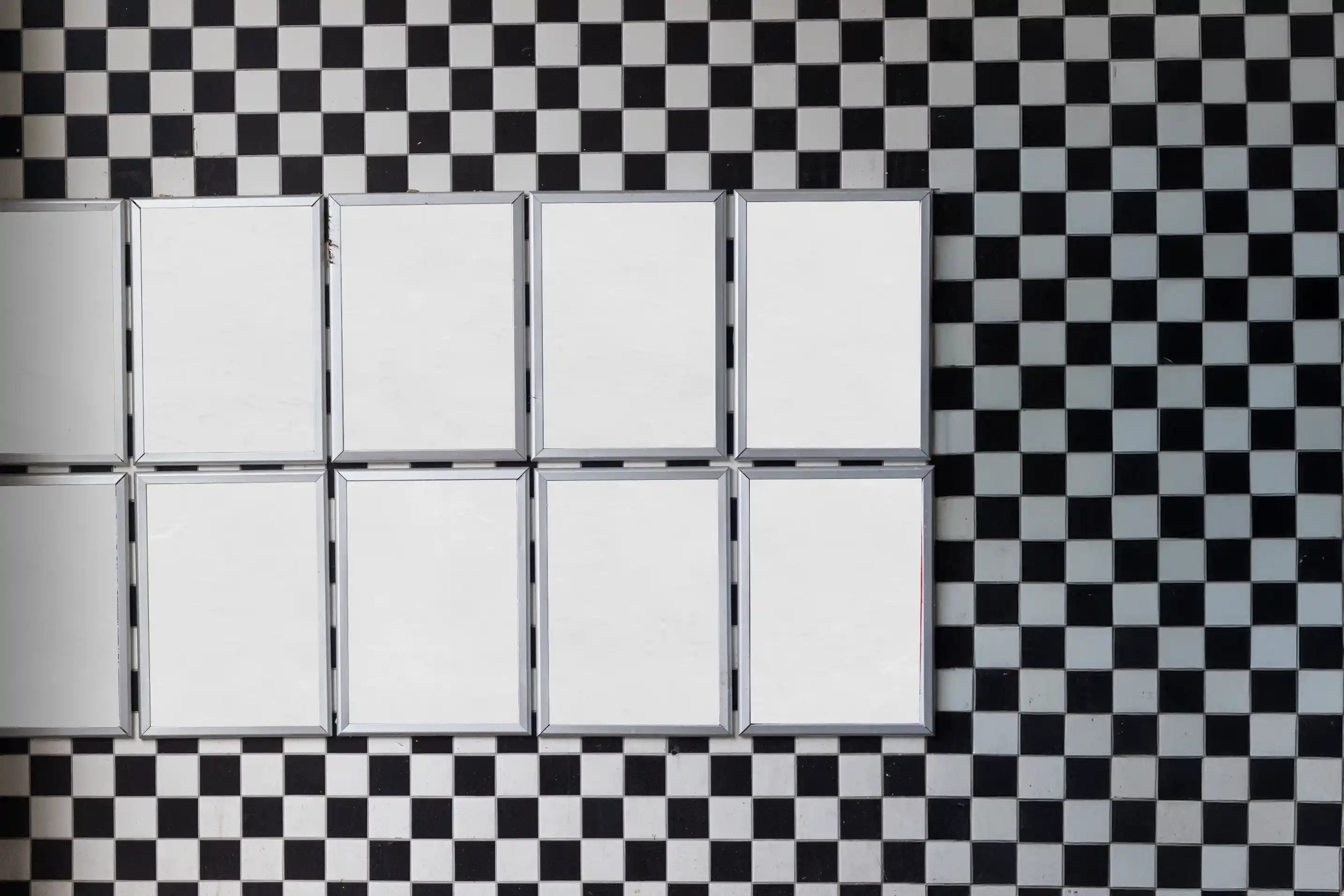 Blank background Amsterdam Haarlemmerdijk wall poster mockup with multiple DIN-format frames mounted on a checkerboard facade in a realistic European city environment.