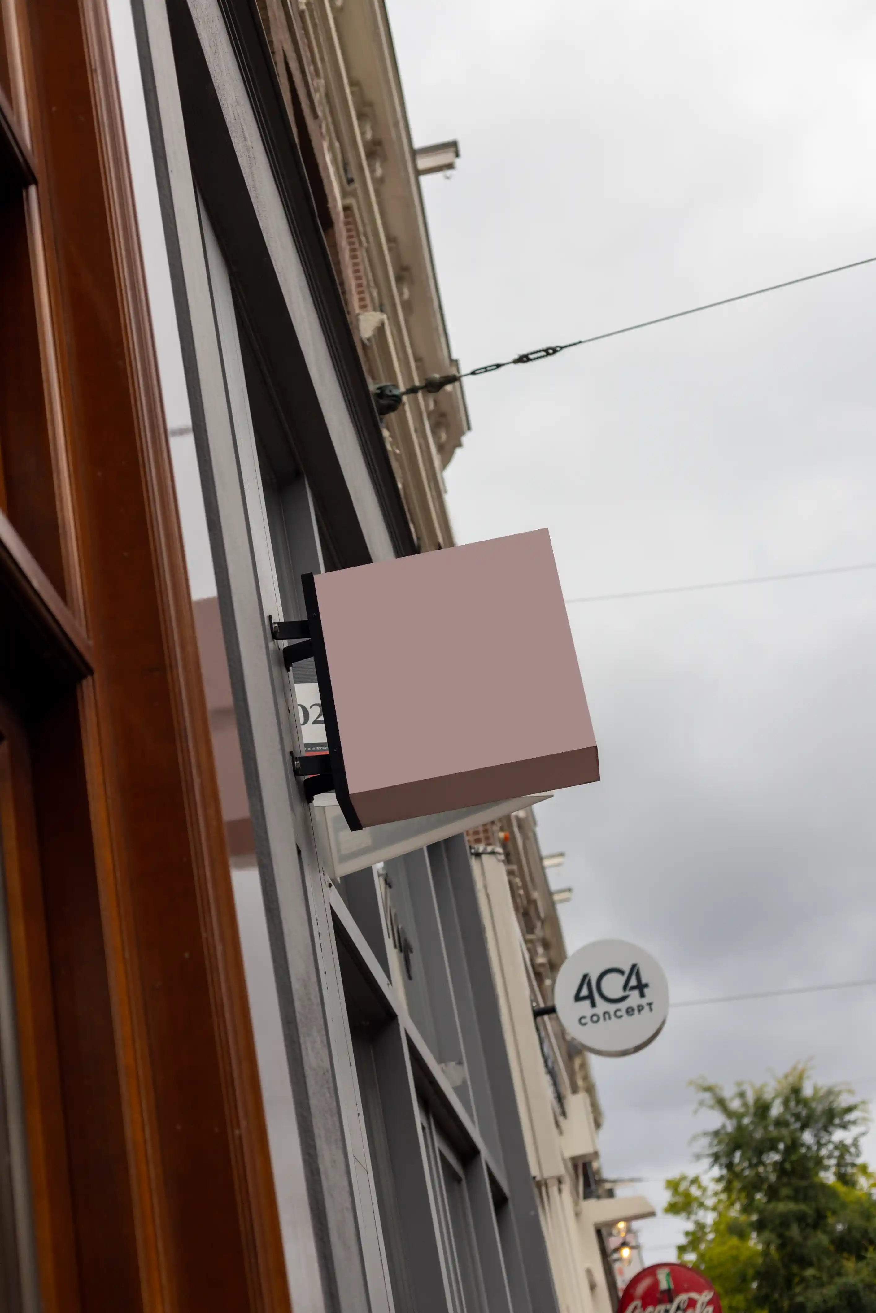 Blank background square hanging store sign mockup in Amsterdam attached to contemporary shop facade, realistic wall mounted signage PSD template for custom branding and retail logo design presentation.