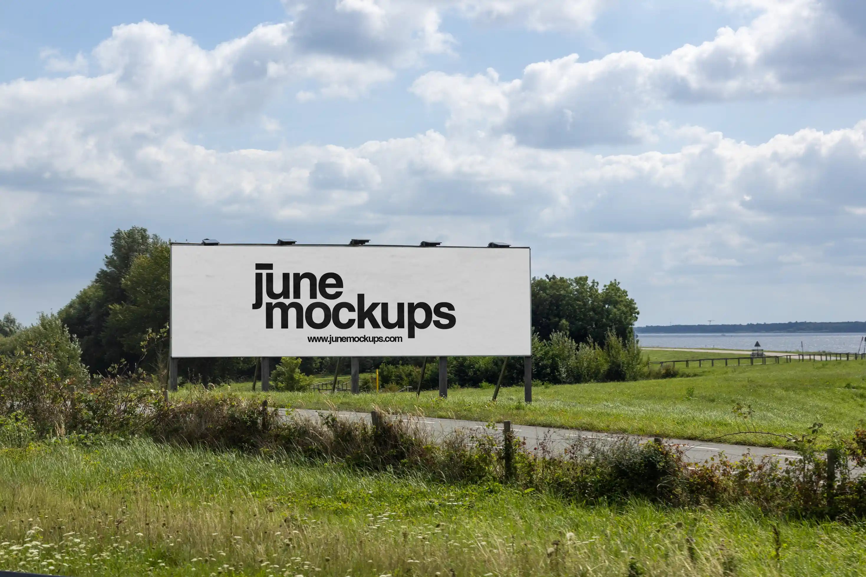 Large landscape roadside billboard mockup near Amsterdam at Almeerderstrand with view towards the Markermeer, realistic outdoor advertising display along Dutch highway surrounded by green fields, high resolution PSD template for campaign presentation.