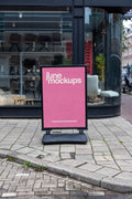 Street poster board mockup in Amsterdam placed on urban sidewalk in front of modern shop window, high resolution PSD template for branding and promotional design.
