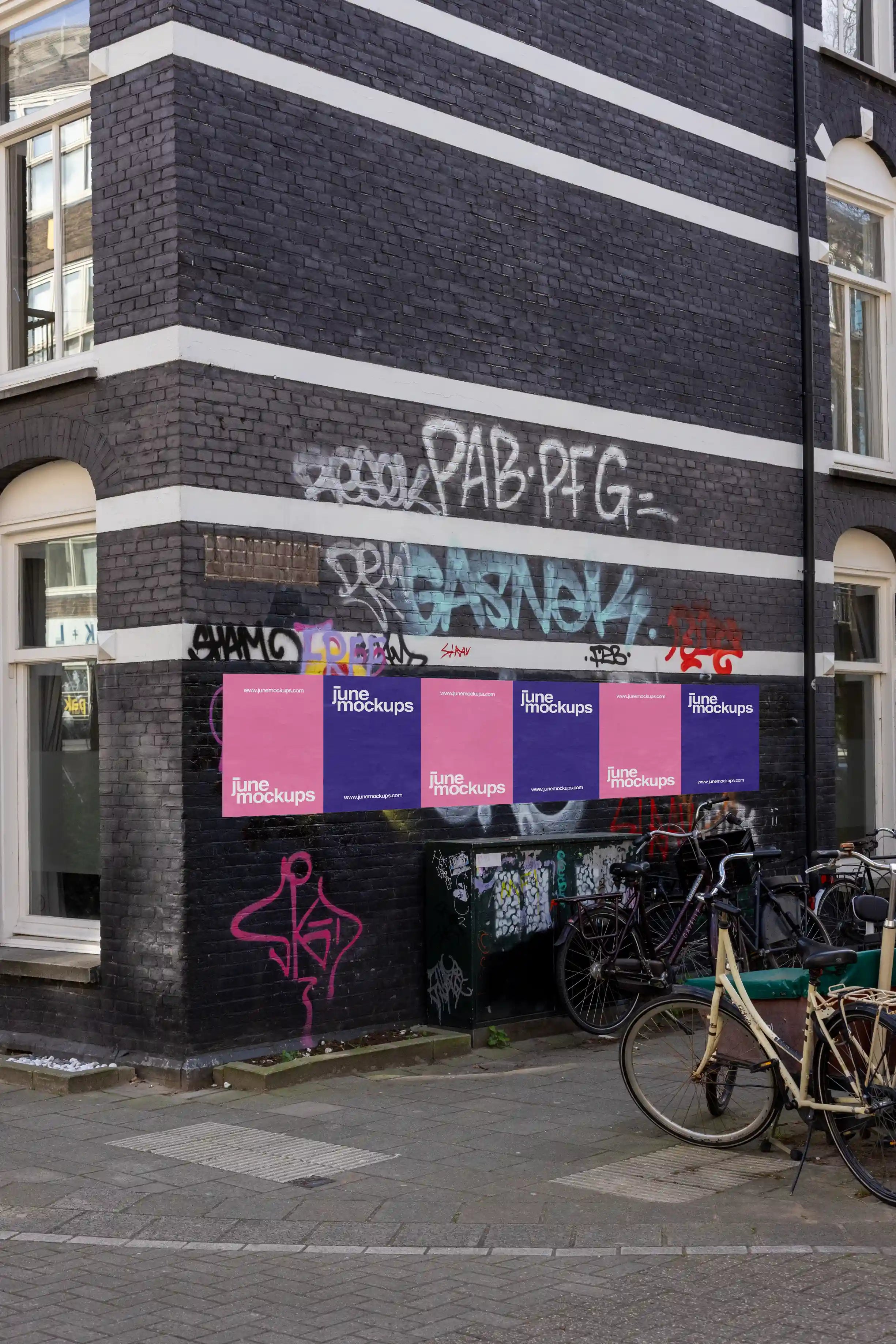 Amsterdam urban poster mockup on black brick graffiti-covered wall with bicycles.