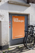 Amsterdam urban street mockup with bright orange poster on white wall and black bicycle in front.