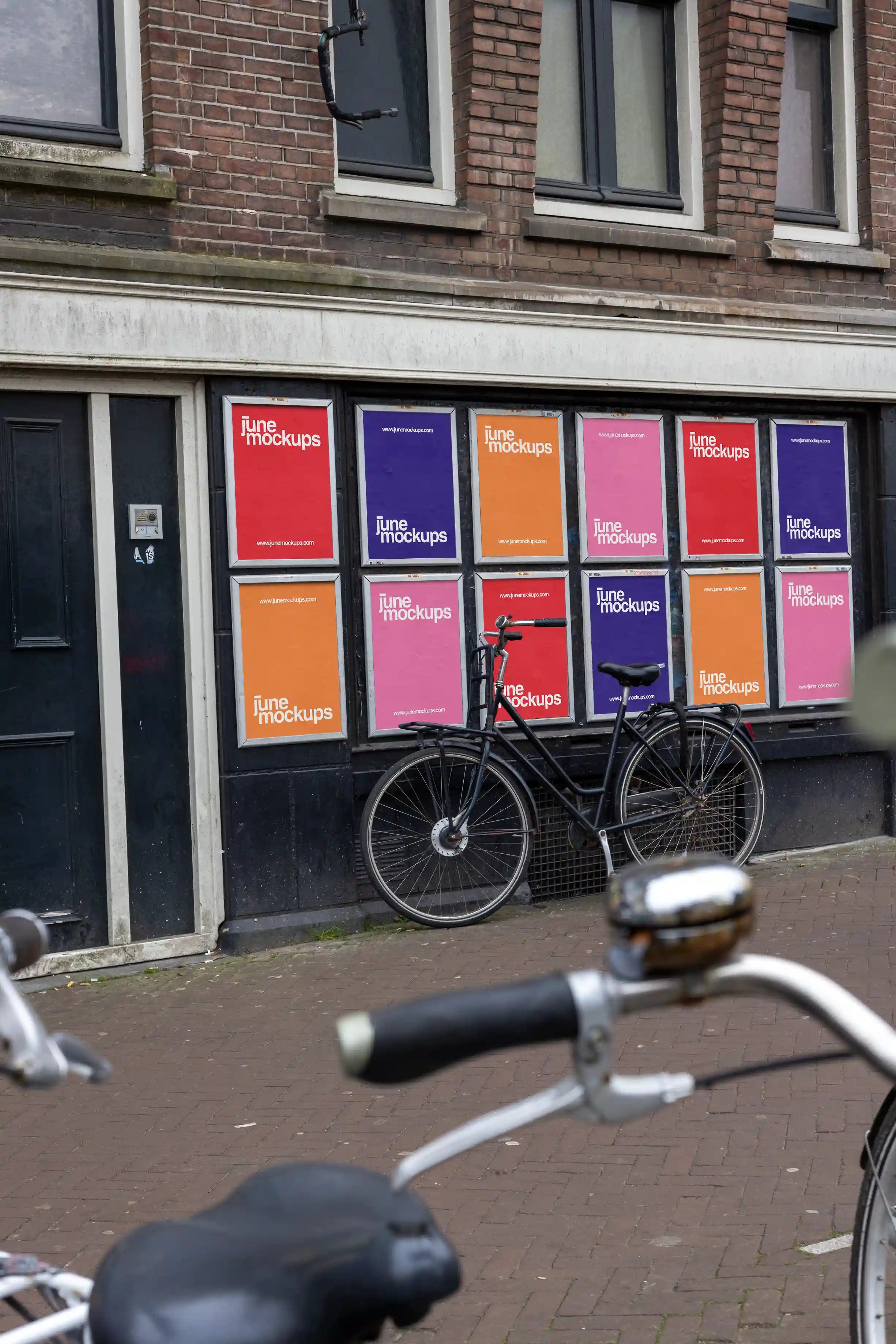 Urban street poster mockups at Muntplein corner in Amsterdam, colorful posters with parked bicycle in front.