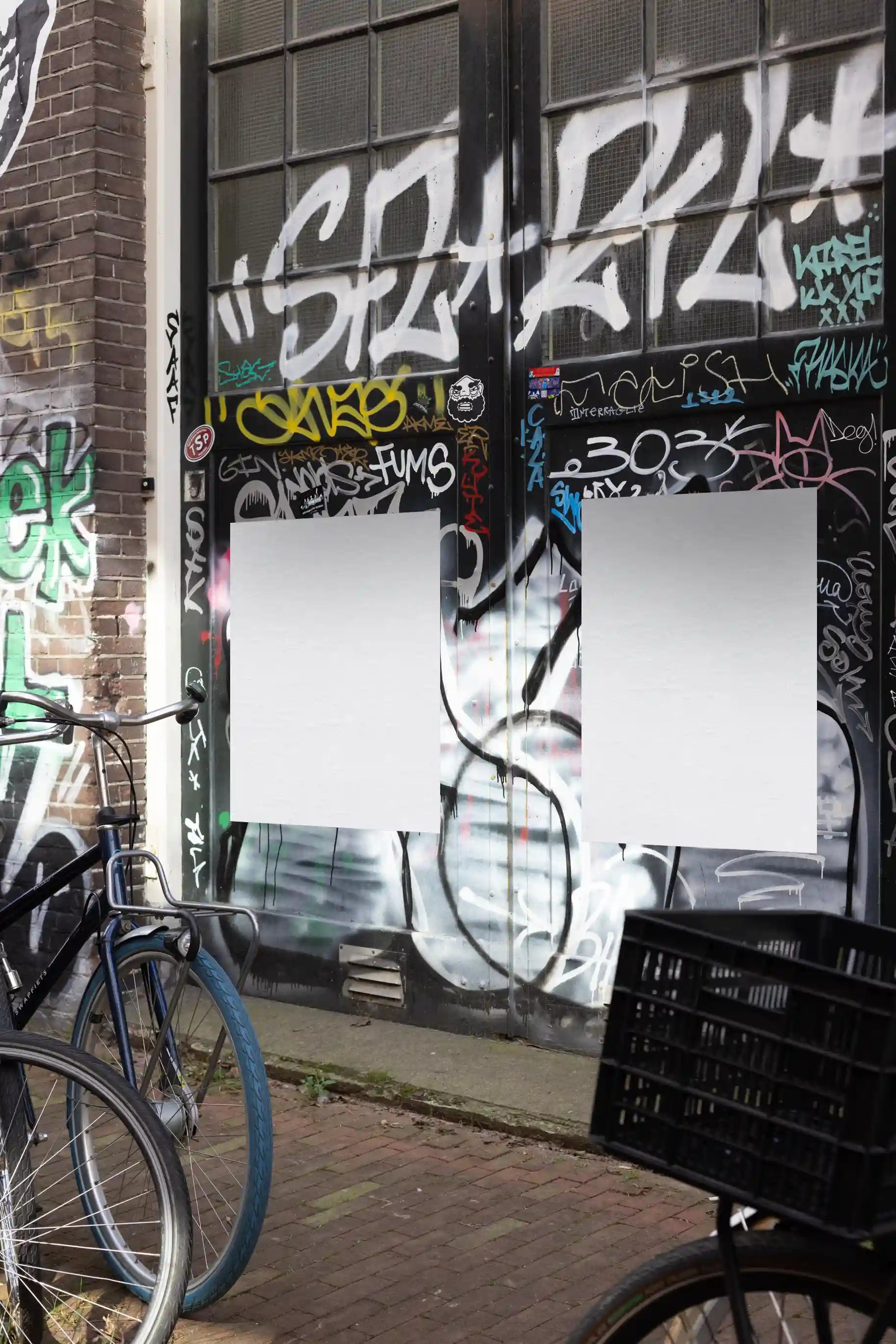 Amsterdam urban street mockup with two white posters, next to parked bicycles in front of a graffiti door.