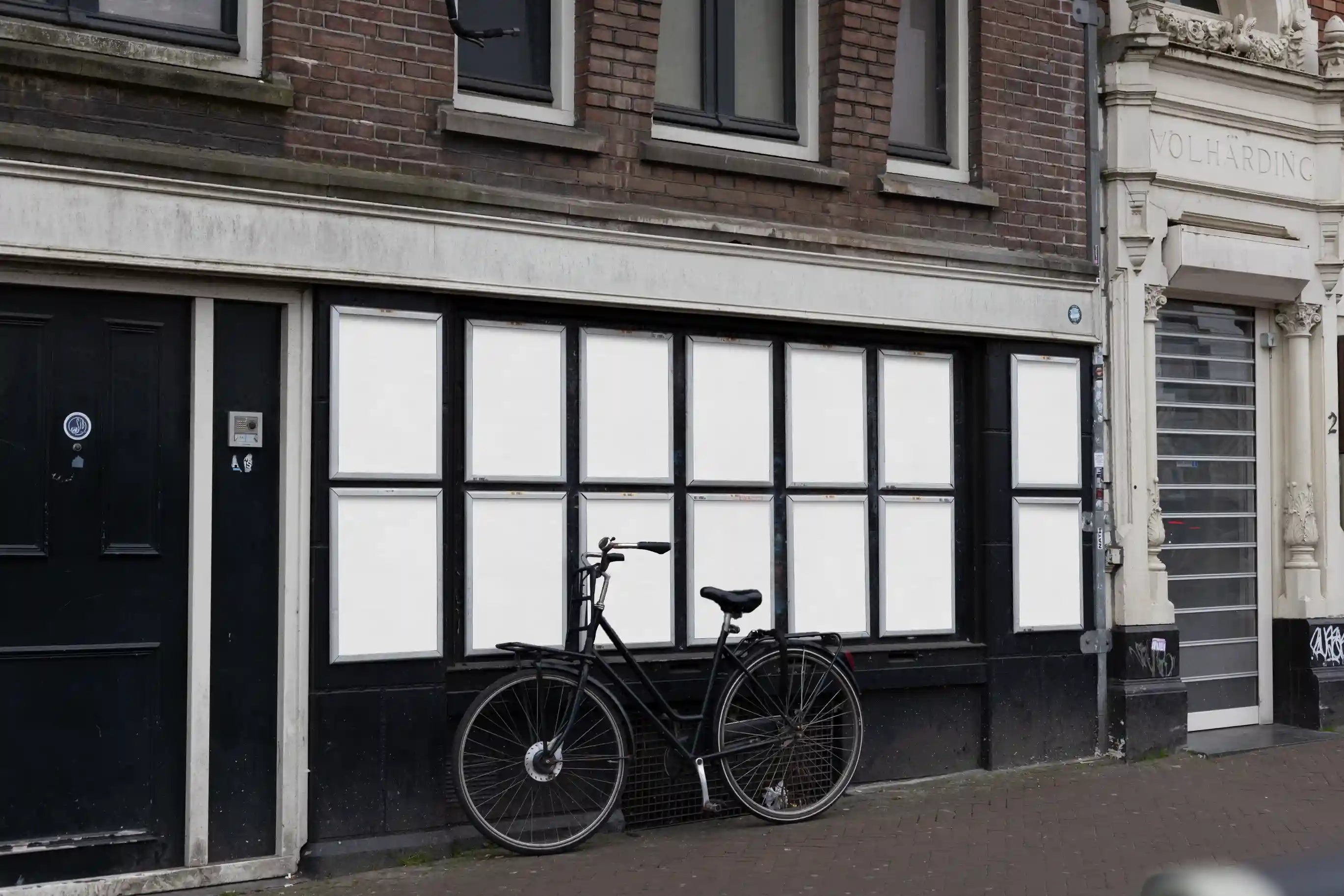 Amsterdam urban street poster mockups on Muntplein corner facade with multiple vibrant posters and a parked bike.