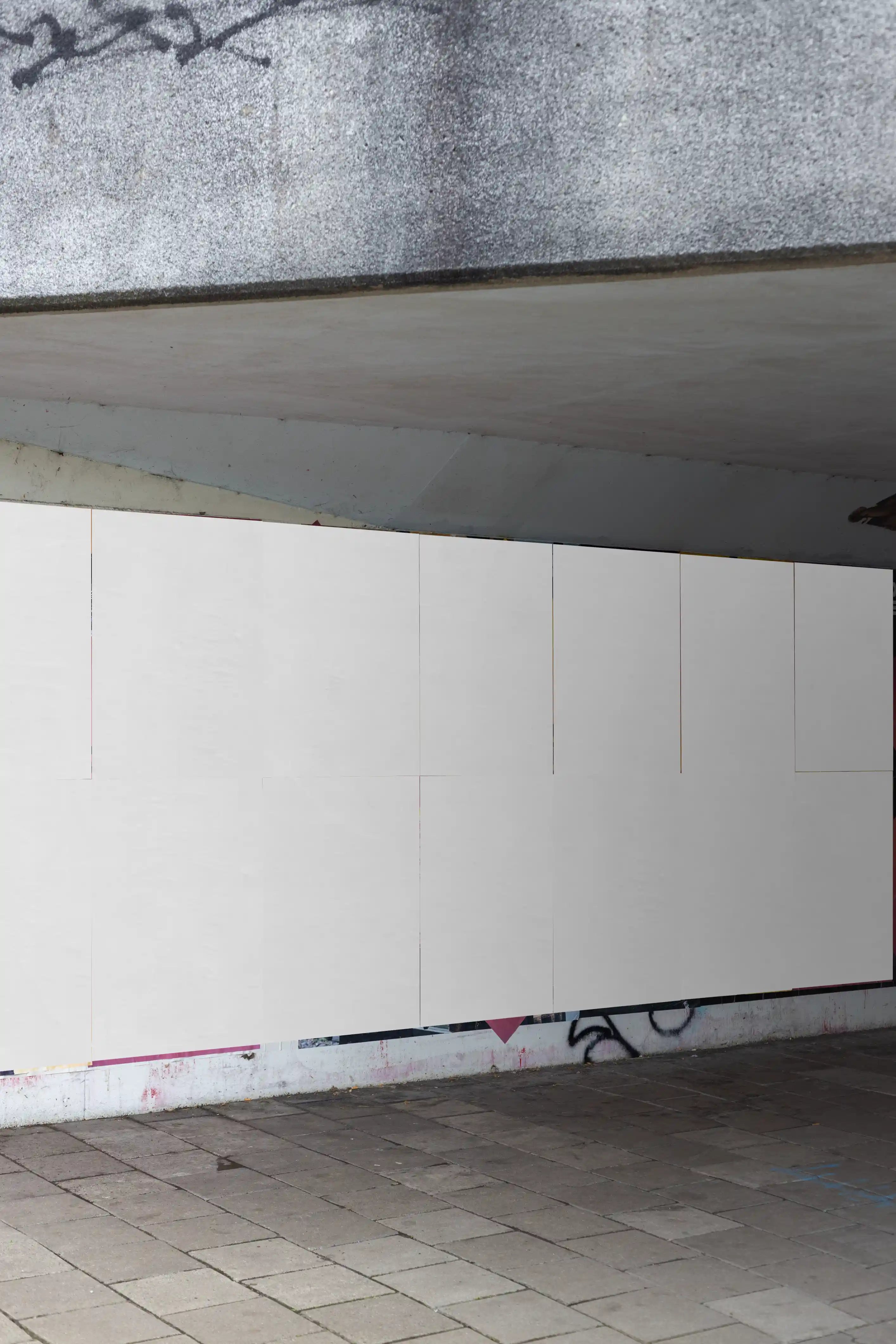 Amsterdam urban wall poster mockup under a concrete bridge featuring multiple DIN-format poster placements with blank background in a realistic street environment with graffiti and tiled pavement.