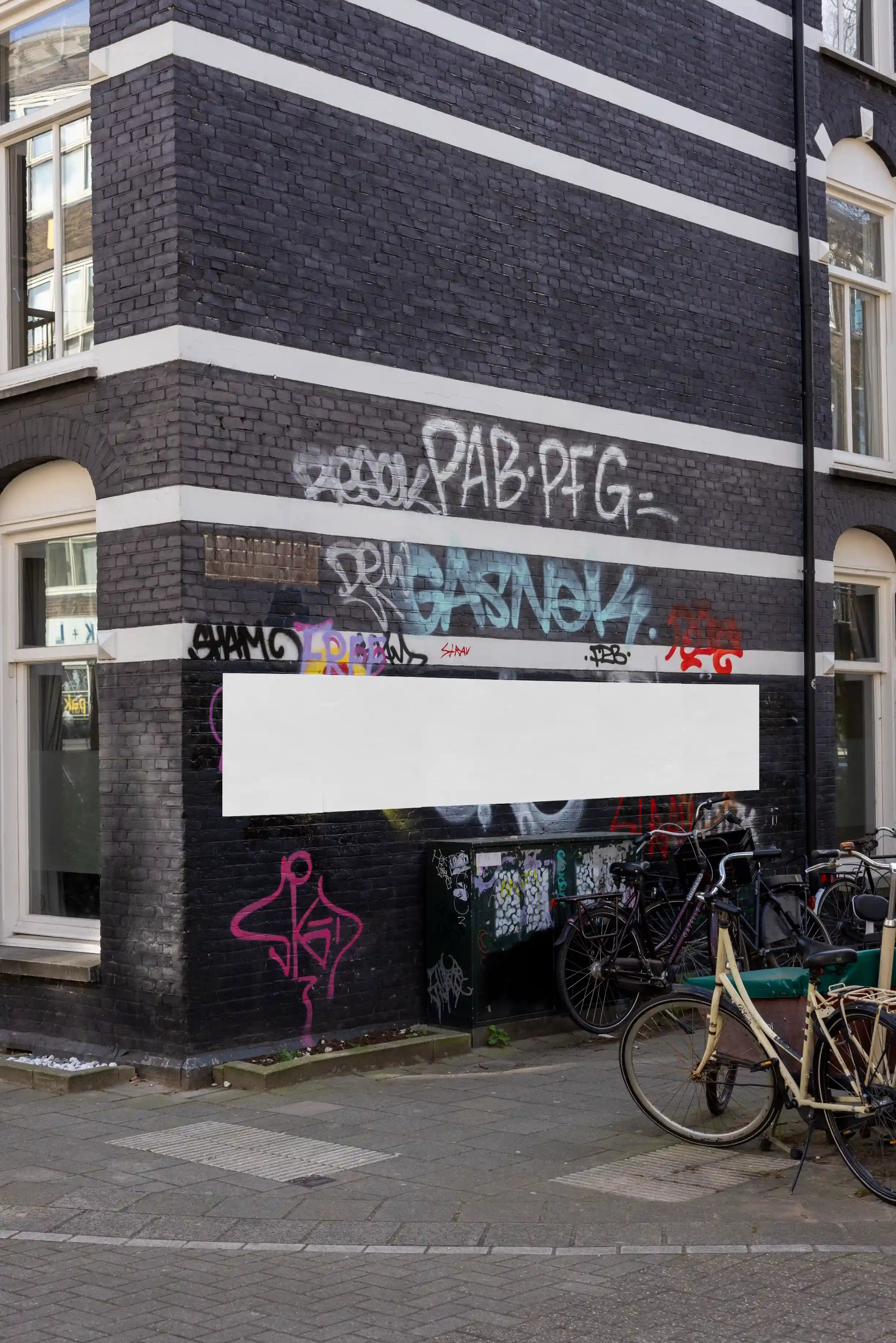 Amsterdam urban poster mockup on black brick graffiti-covered wall with bicycles.