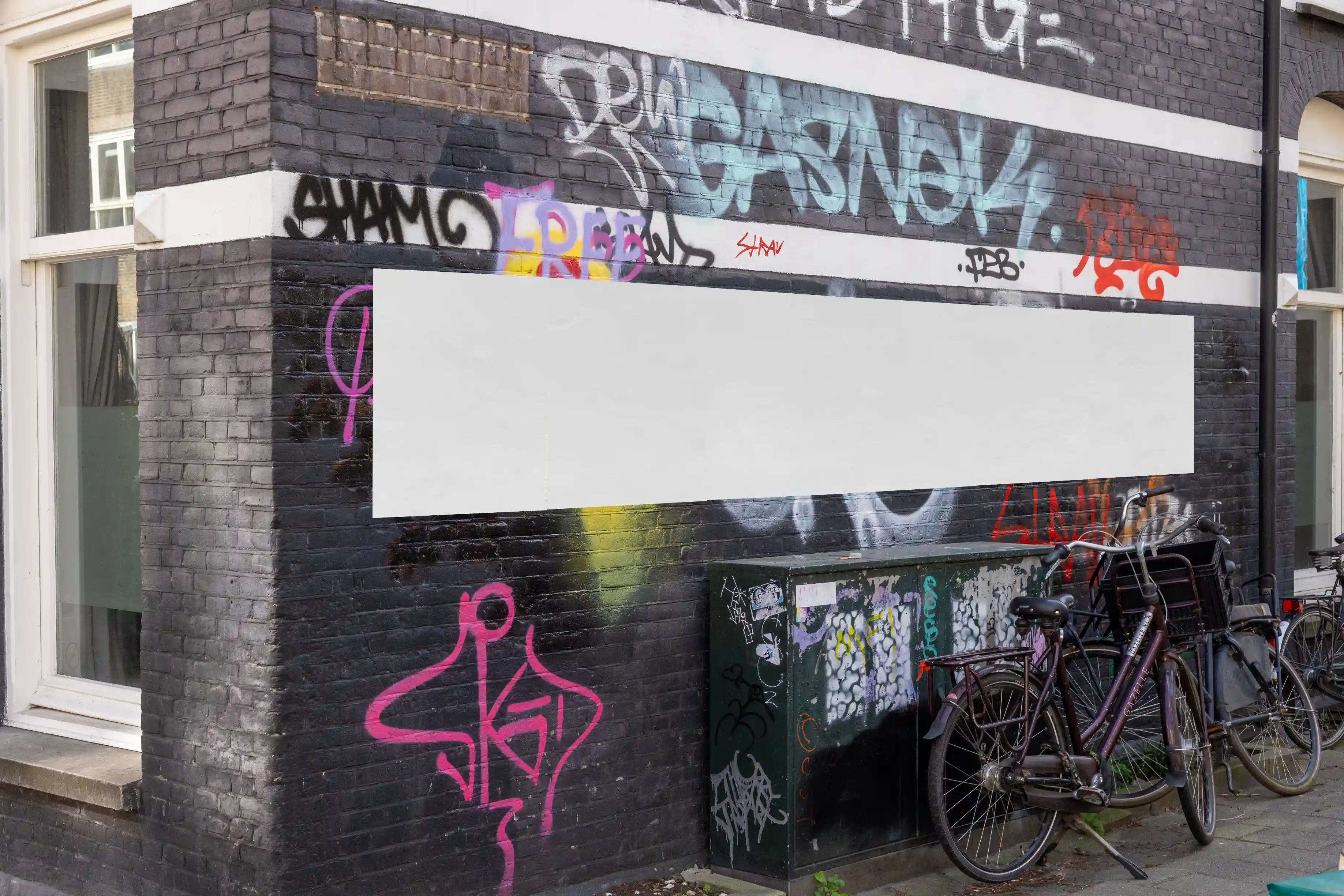Amsterdam urban poster mockup on black brick graffiti-covered wall with bicycles.