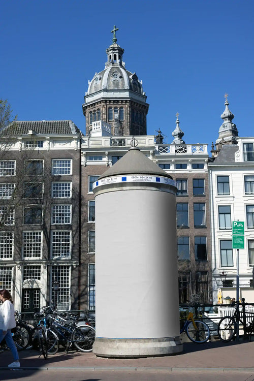 Cylindrical billboard mockup in central Amsterdam with historic architecture and St. Nicholas Basilica in the background
