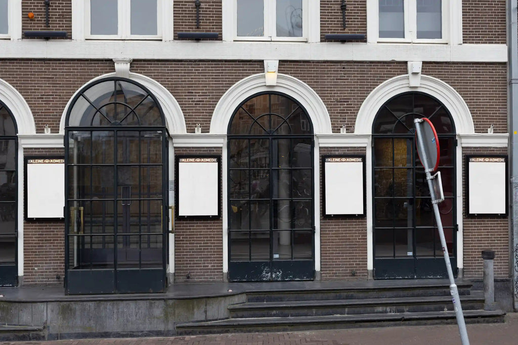 City light poster mockups at the entrance of De Kleine Komedie theater in Amsterdam, white posters under arched windows.