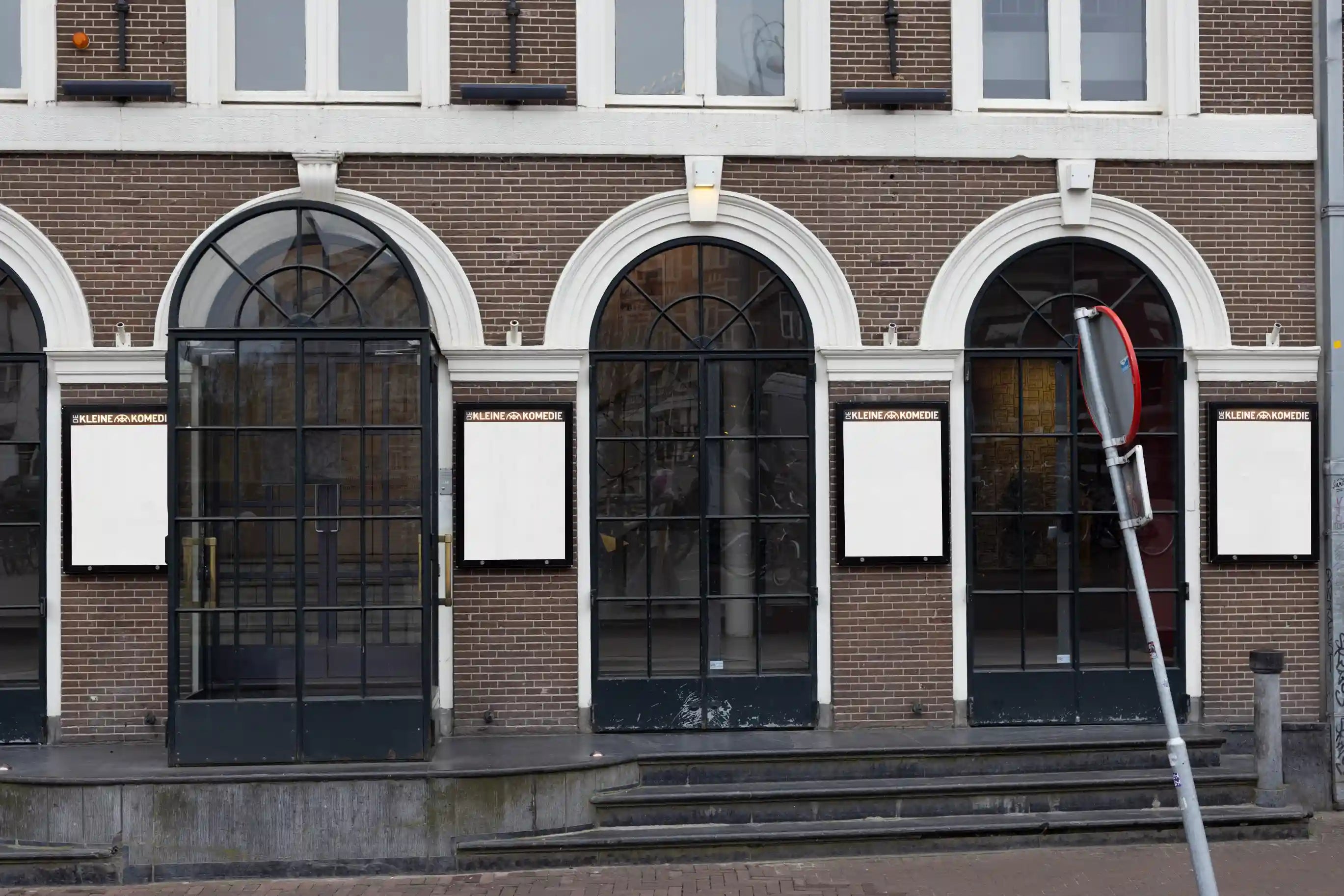 City light poster mockups at the entrance of De Kleine Komedie theater in Amsterdam, white posters under arched windows.
