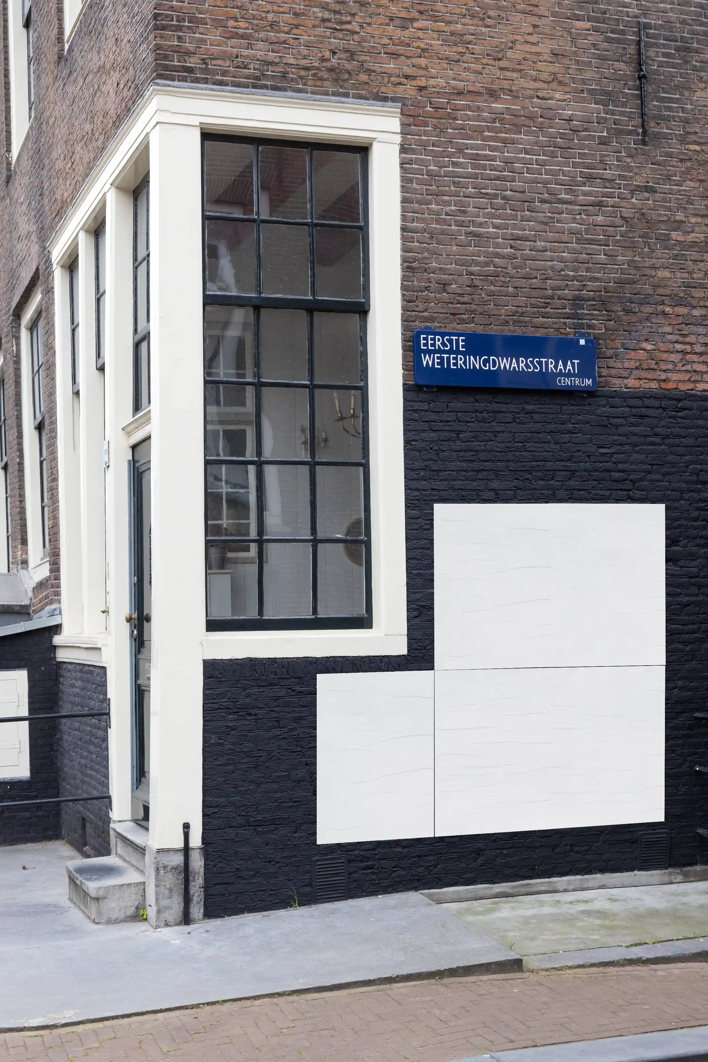 Amsterdam urban street poster mockup at Eerste Weteringdwarsstraat, colorful posters displayed on a black-painted brick wall.