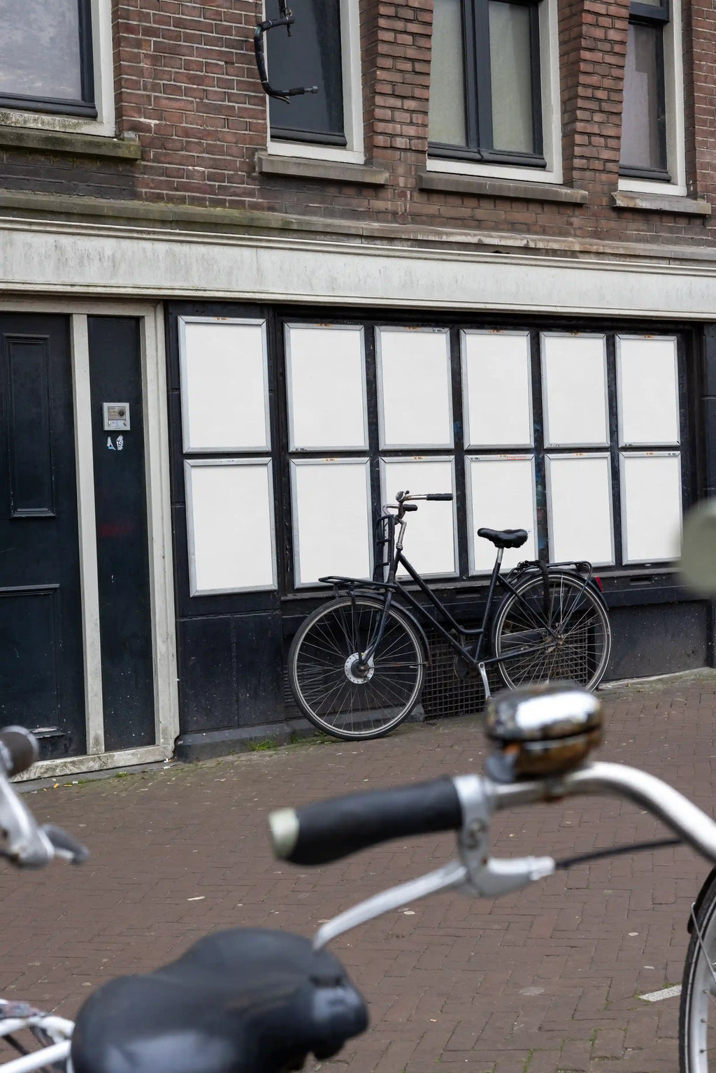 Urban street poster mockups at Muntplein corner in Amsterdam, colorful posters with parked bicycle in front.