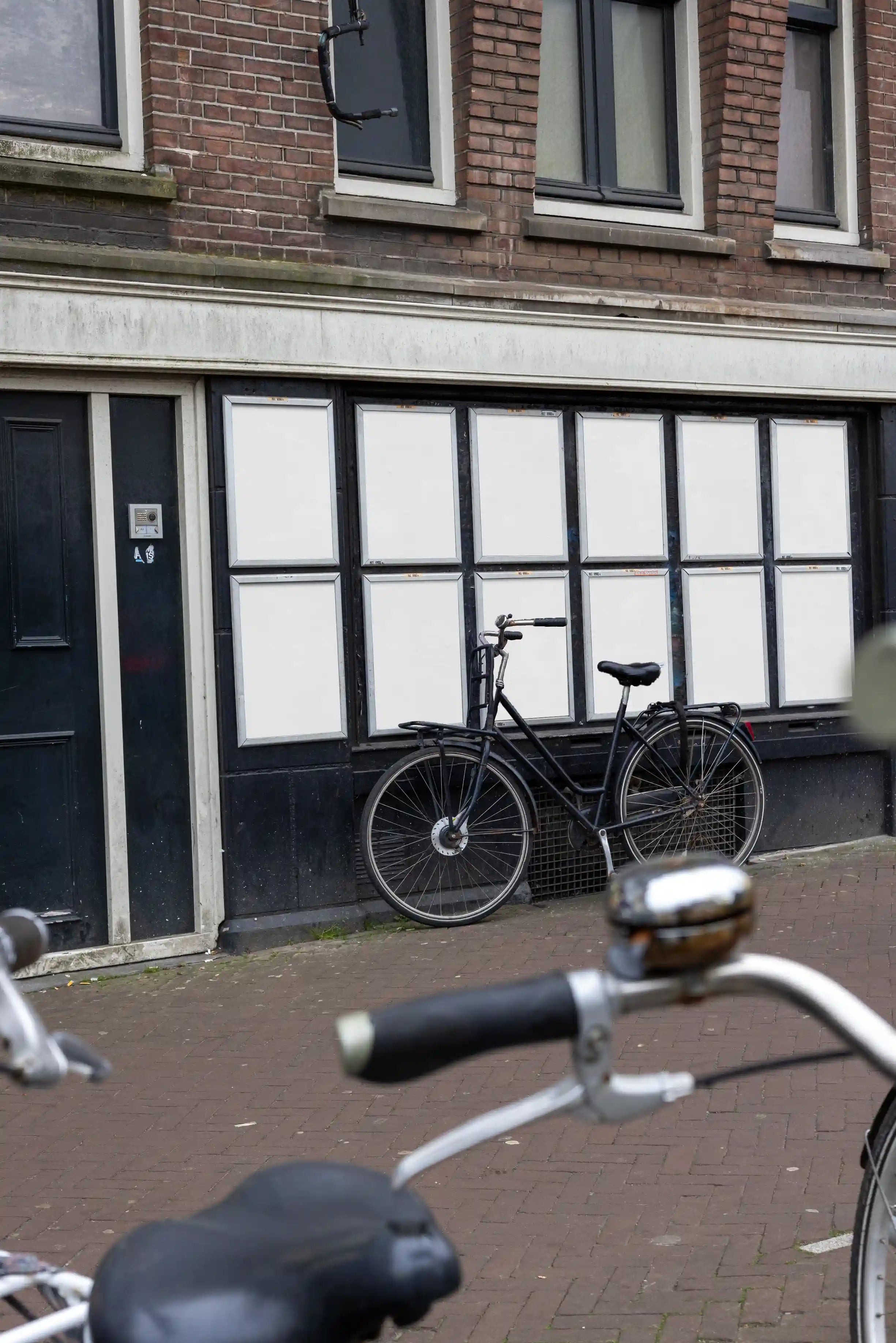 Urban street poster mockups at Muntplein corner in Amsterdam, colorful posters with parked bicycle in front.