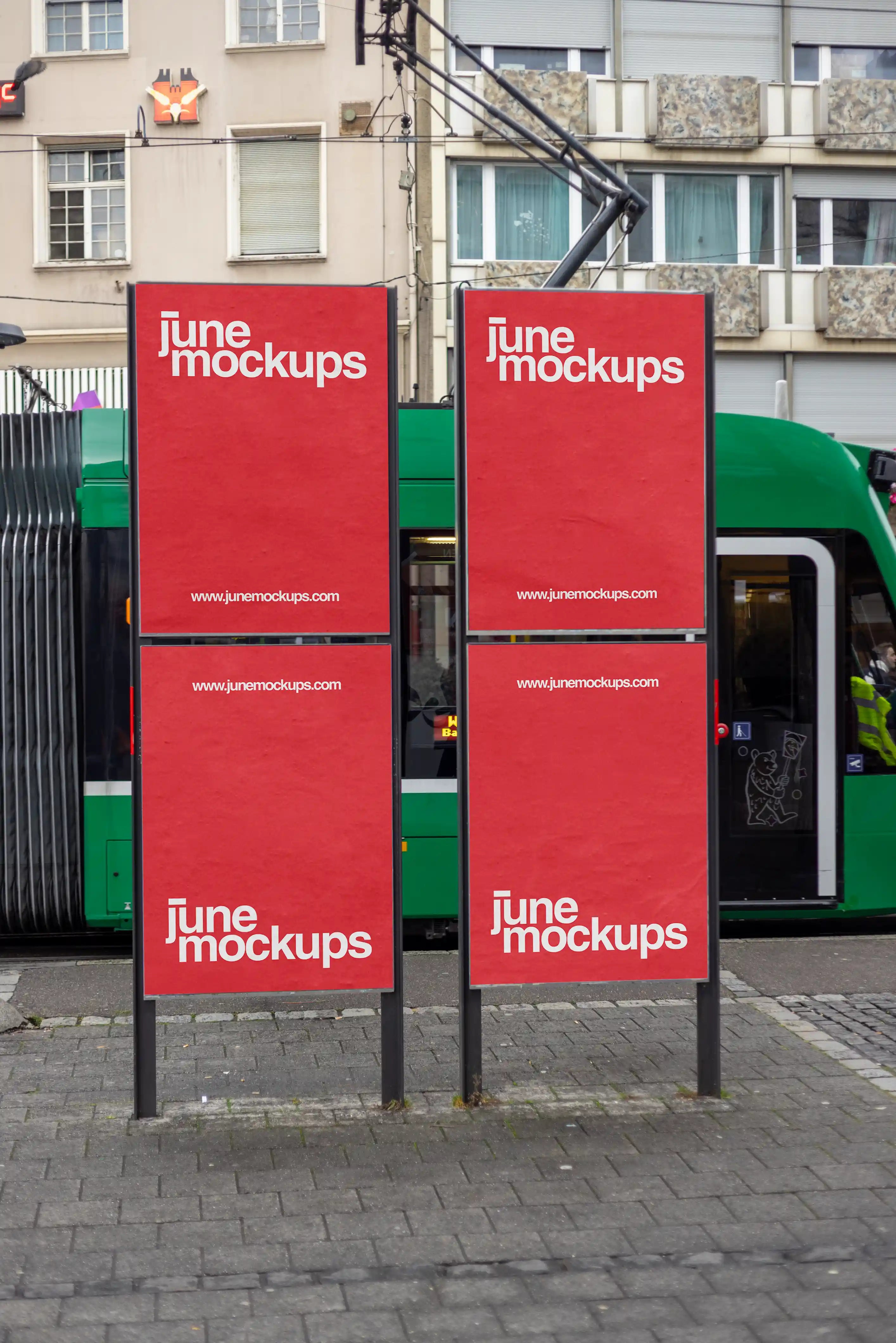 Four red DIN poster mockups on two outdoor advertising stands at Claraplatz in Basel, with a green tram passing in the background. The urban scene includes city buildings, pavement and public transport details, designed for transit advertising, poster campaigns and out-of-home branding presentations.