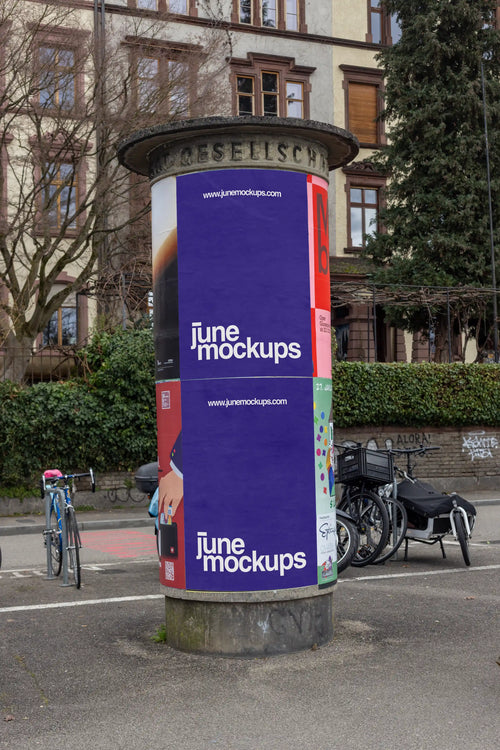 Purple two-part poster mockup on a cylindrical ad column near the Rhine in Basel. The scene includes bicycles, trees, residential buildings, street markings and authentic riverside surroundings, created for realistic Litfaßsäule, poster campaign and out-of-home advertising presentations.