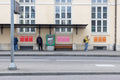 Nine small DIN poster mockups displayed in groups of three along a tram stop wall in Basel. The scene shows a public transport stop with a bench, ticket machine, blurred pedestrians, street tracks and a light building facade in the background.