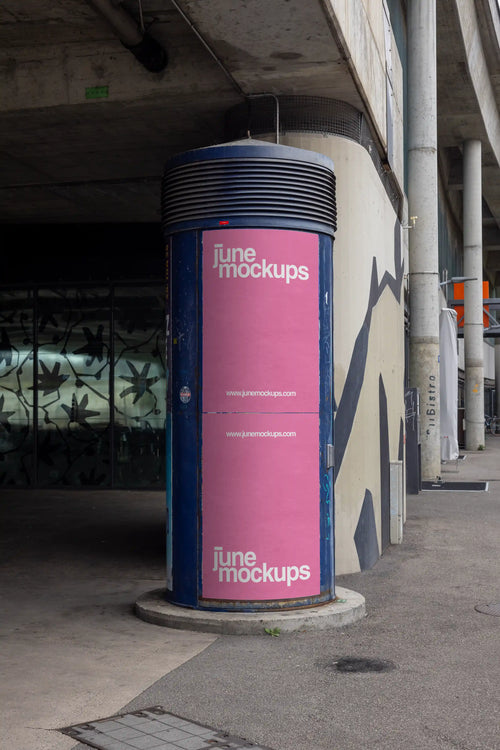 Pink two-part DIN poster mockup on a blue cylindrical advertising column in Basel under a concrete bridge structure. The scene includes urban shadows, worn surfaces, concrete architecture and street details, made for realistic Litfaßsäule, ad column and poster campaign presentations.
