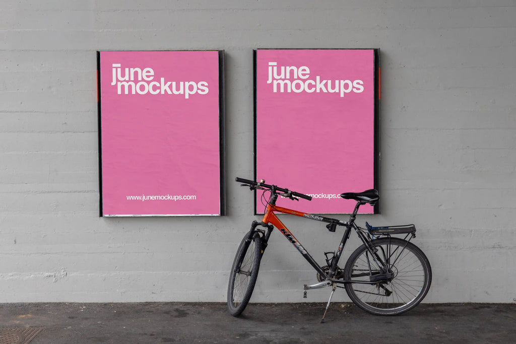 Two pink DIN poster mockups mounted side by side on a grey concrete wall under a bridge in Basel. A black and orange bicycle leans in front of the right poster, with realistic paper texture, soft shadows, dark floor details and an urban underpass atmosphere.