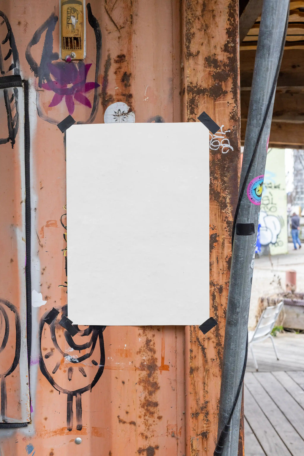 Blank white A4 or A3 poster mockup taped to a rusty wooden wall at Holzpark Klybeck in Basel, near Gannet. The poster is surrounded by black tape, graffiti marks, stickers, worn paint and industrial textures, offering a realistic raw street poster setting for flyers, art prints and campaign design previews.