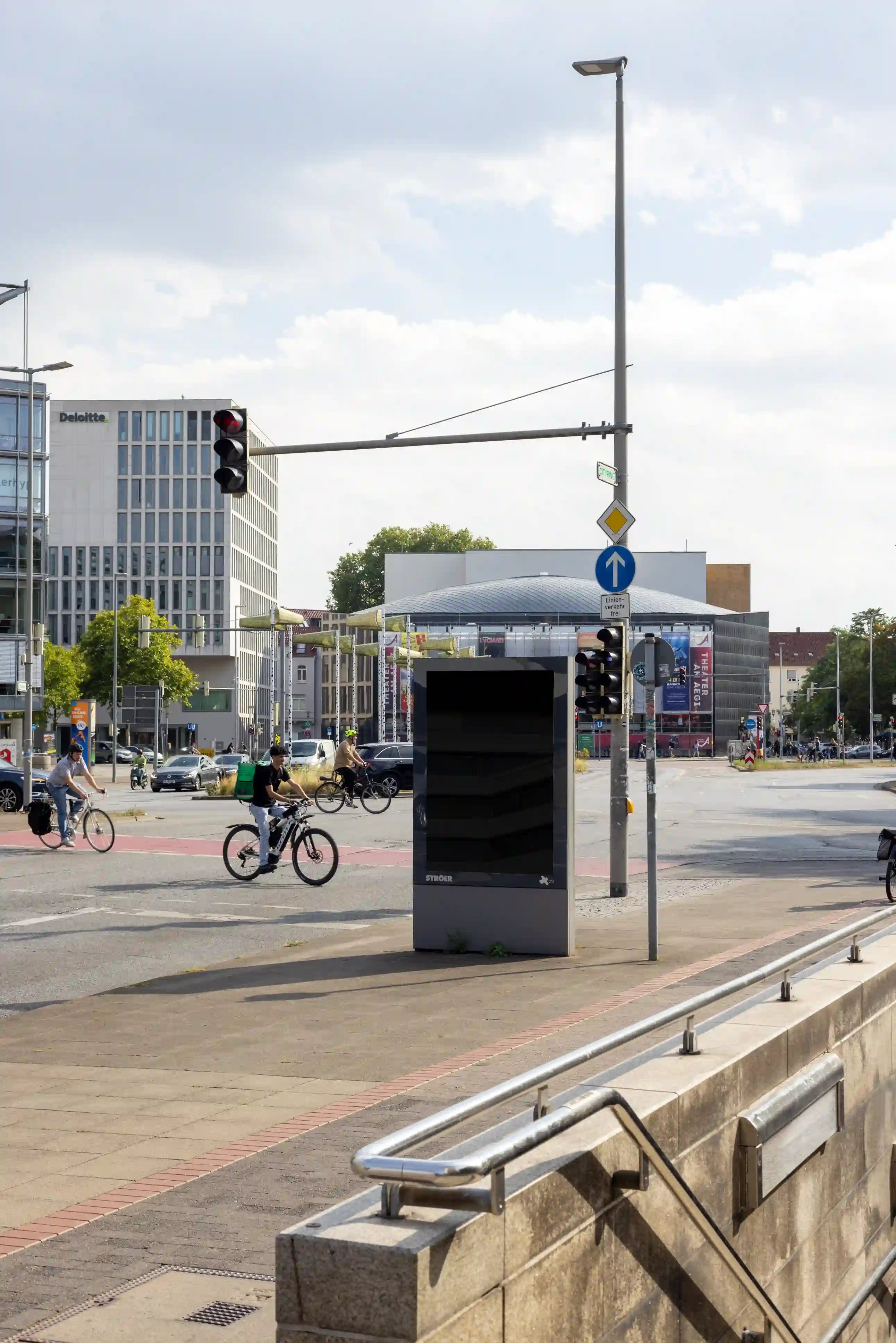 Blank city light advertising mockup at a busy intersection in Hanover’s Aegidientorplatz. Features authentic reflections, perspective, and soft daylight for realistic outdoor branding presentations.
