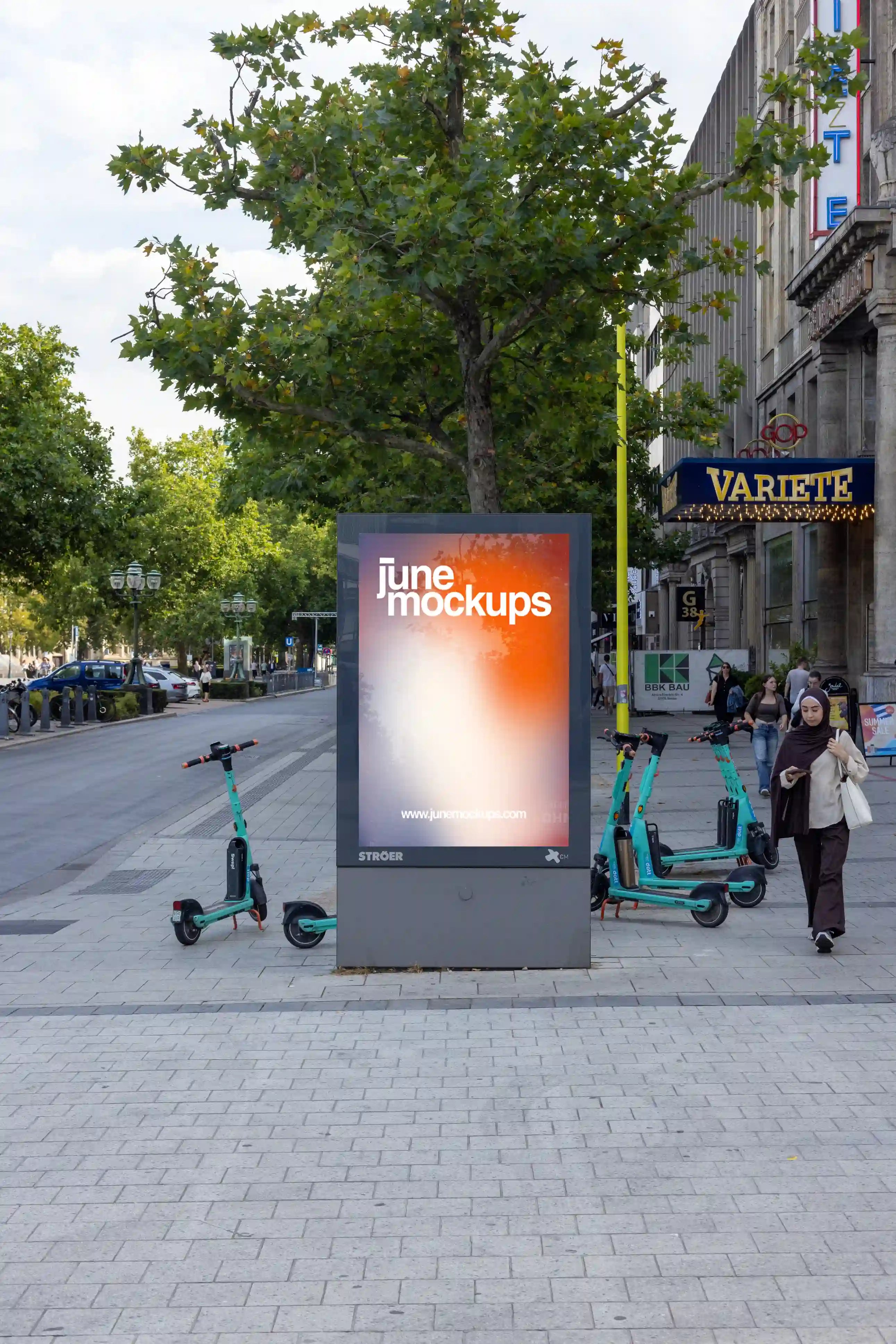 City light poster mockup in Hanover at Kröpcke, directly by the GOP Varieté Theater and Opera House. Modern illuminated advertising display surrounded by scooters and city life. Perfect for elegant, urban advertising visuals.
