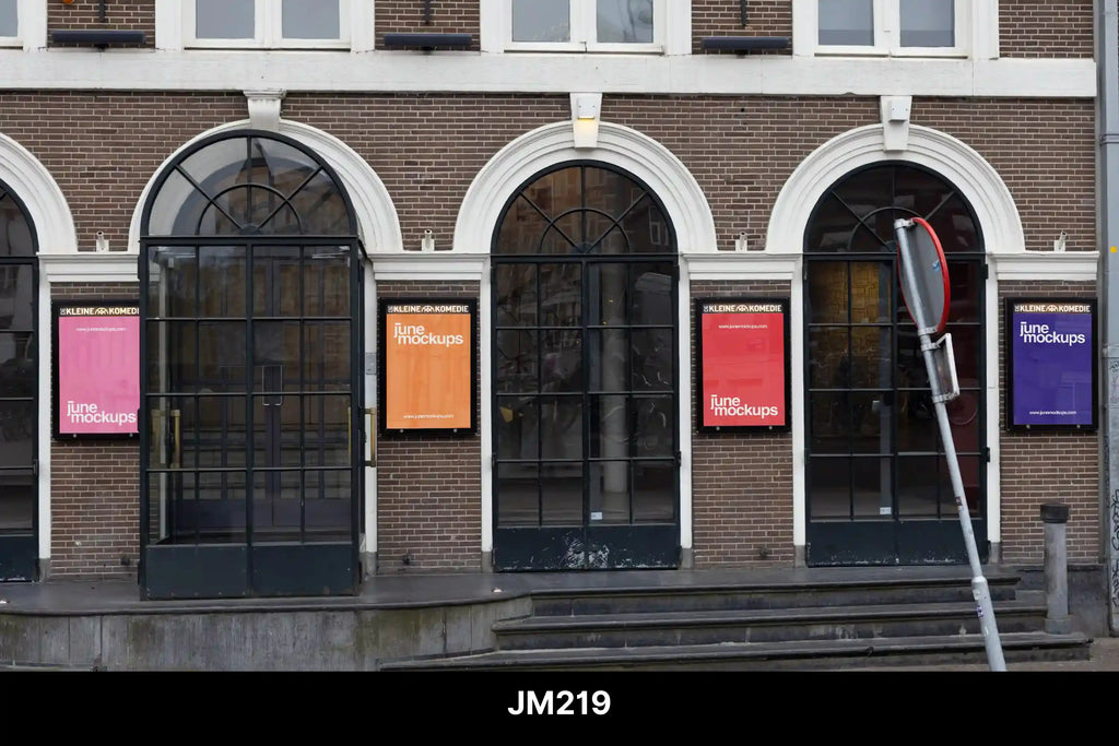A row of red, pink, orange, and purple posters displayed between tall arched windows on a historic brick building. Perfect for professional presentation — upload your artwork and get a realistic poster mockup placed for you.