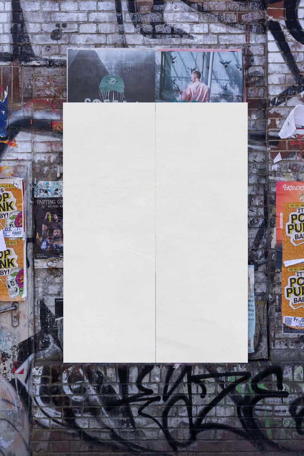Blank poster wall mockup on a textured brick surface with graffiti elements. Designed for overlaying custom poster artwork, providing authentic lighting and urban realism.