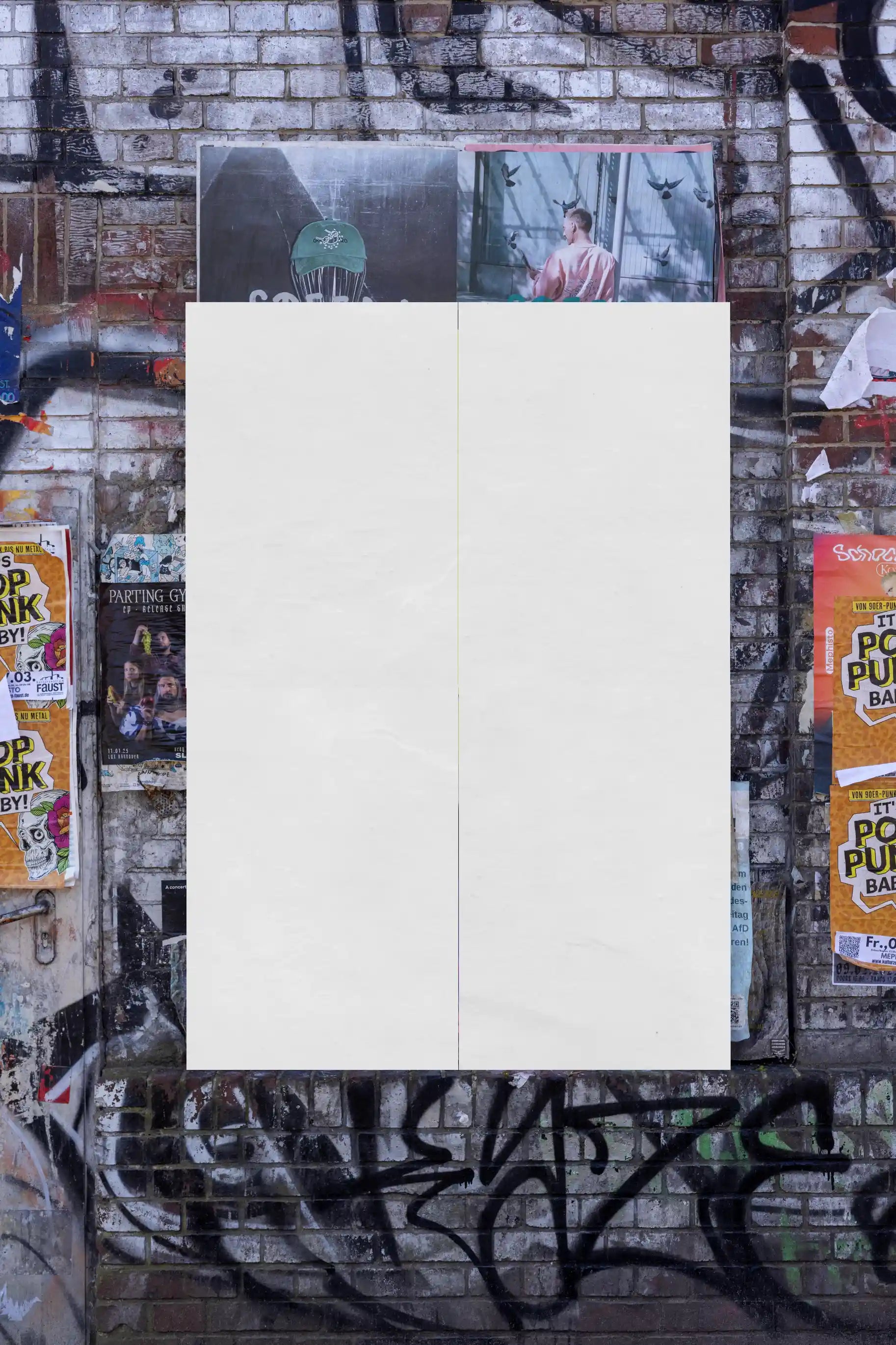 Blank poster wall mockup on a textured brick surface with graffiti elements. Designed for overlaying custom poster artwork, providing authentic lighting and urban realism.