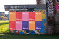 High-resolution urban wall mockup showing multiple colorful posters pasted on a graffiti-covered wall in Hanover. Natural daylight, shadow play, and paper seams create a vivid, realistic street design scene perfect for branding or art campaigns.