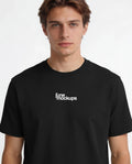 Close-up studio t-shirt mockup showing a male model wearing a black shirt with front logo print placement, realistic fabric texture and clean lighting, perfect for streetwear brands, logo mockups, apparel branding and merch design previews.