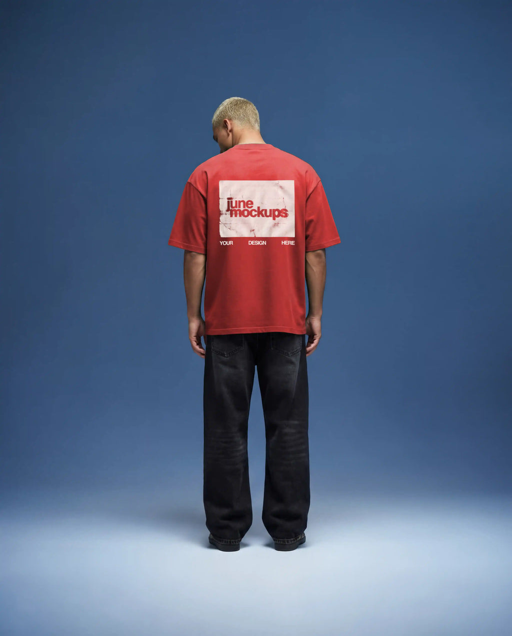 Red oversized t-shirt mockup back view with bold back print placement, natural fabric texture and realistic lighting, worn by model in minimal studio with blue backdrop, high quality apparel mockup for fashion branding, streetwear design and merch presentation.