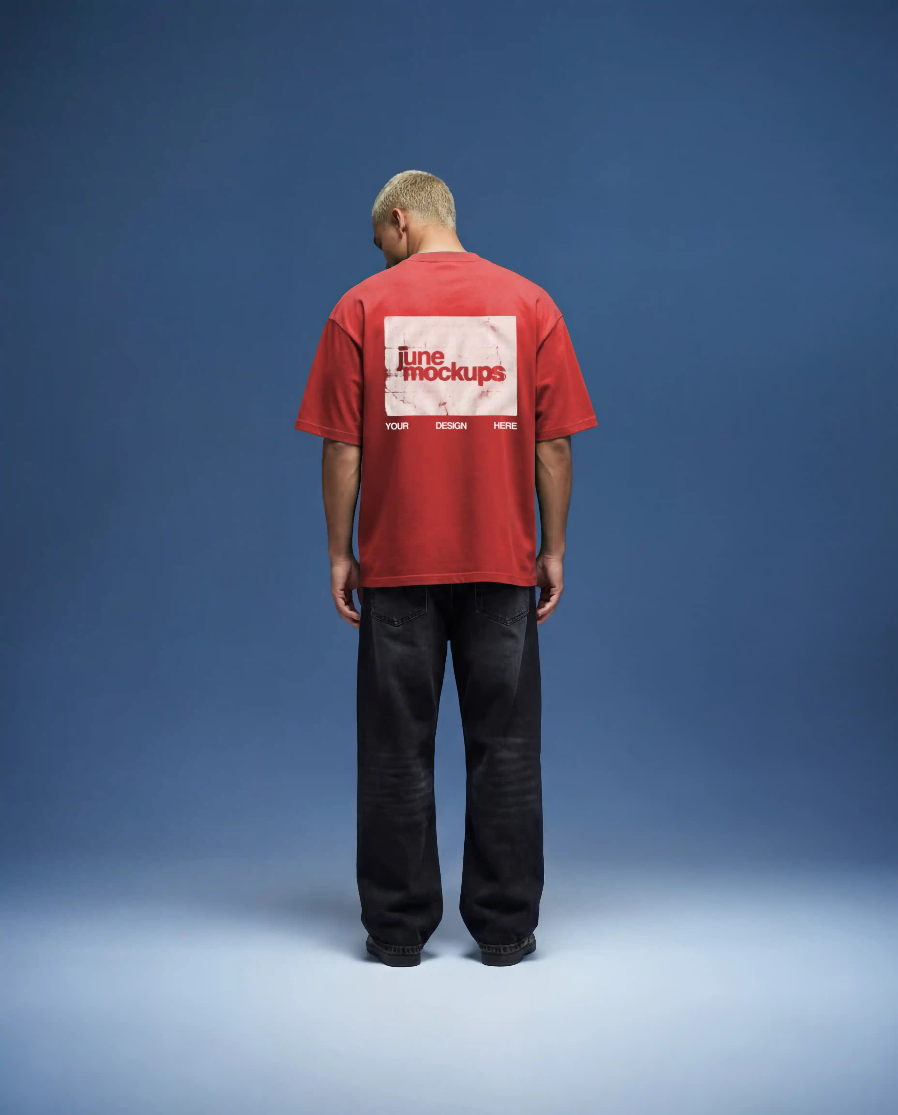Red oversized t-shirt mockup back view with bold back print placement, natural fabric texture and realistic lighting, worn by model in minimal studio with blue backdrop, high quality apparel mockup for fashion branding, streetwear design and merch presentation.