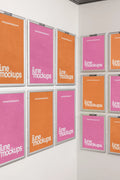 Twelve framed DIN poster mockups arranged across two white indoor walls in a corner layout. The posters are displayed in silver frames with pink and orange designs, creating a clean gallery-style wall for presenting multiple poster artworks in one realistic scene.