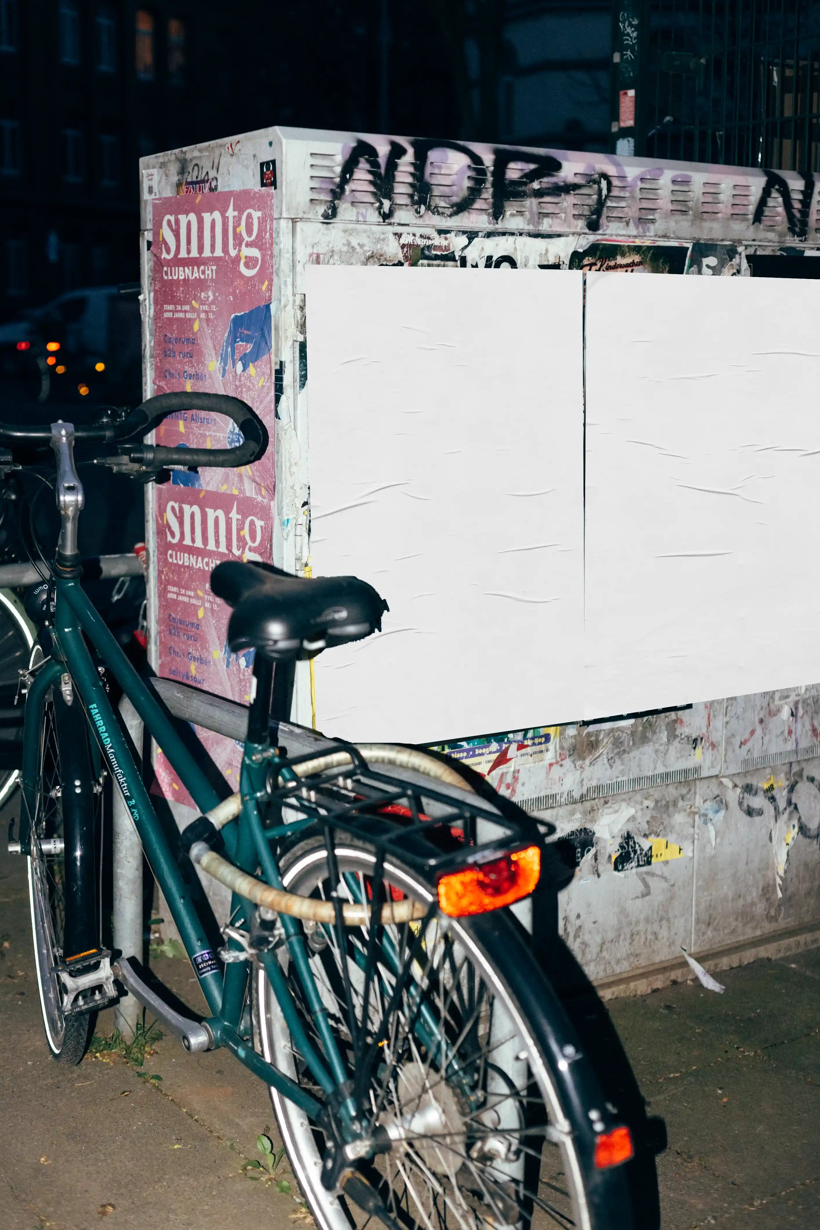 Urban poster mockup at night with blank posters on a grunge wall next to a bicycle, capturing a realistic city advertising scene with authentic lighting and textures.