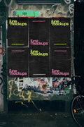 Urban poster mockup showing multiple black posters arranged in a grid on a textured street wall with layered paper details, ideal for realistic outdoor advertising and branding presentations.